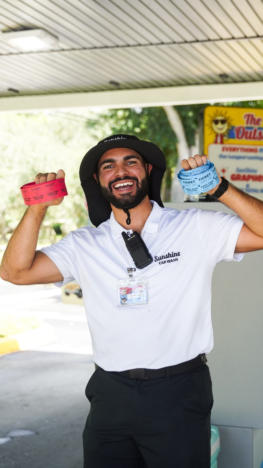 A smiling Sunshine greeter showing off colorful wash ticket wristbands