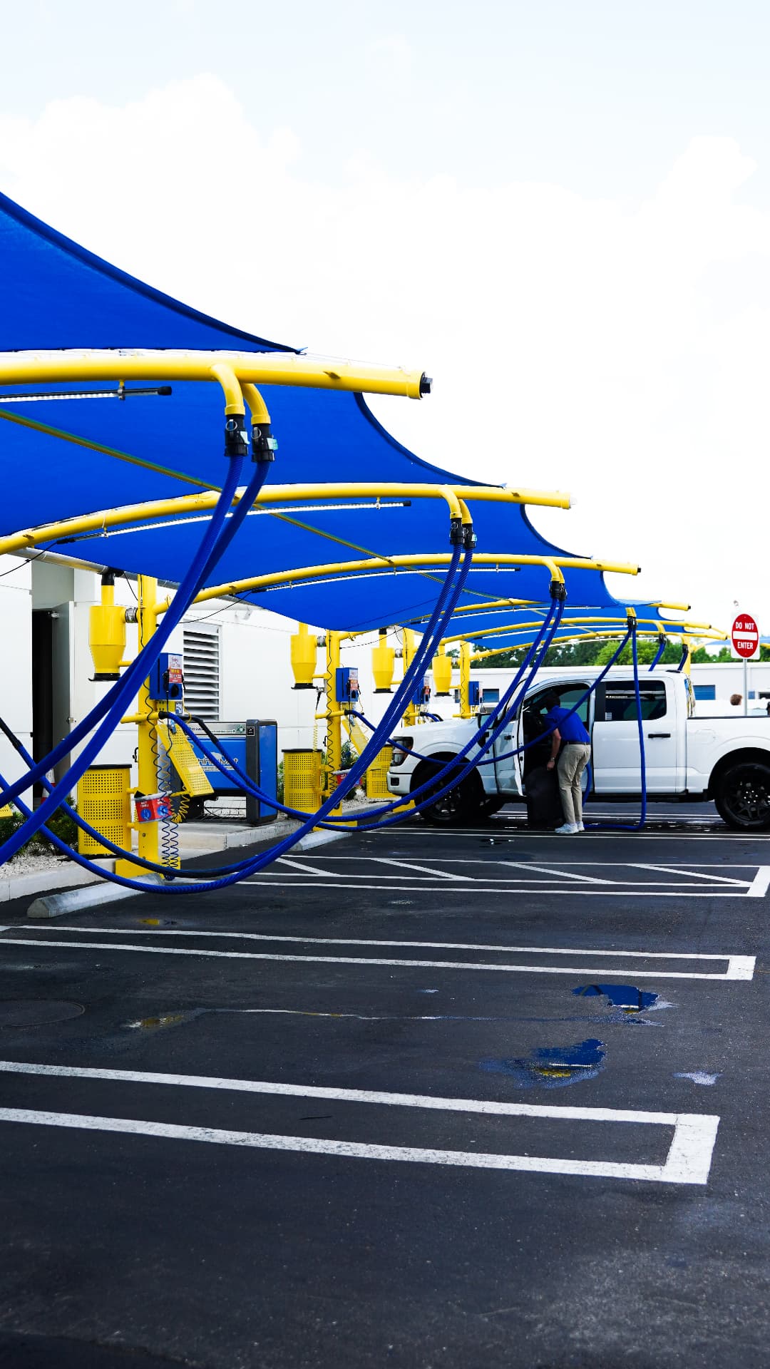 Free vacuum stations under bright blue canopies at a Sunshine Car Wash, with a customer cleaning out a white truck