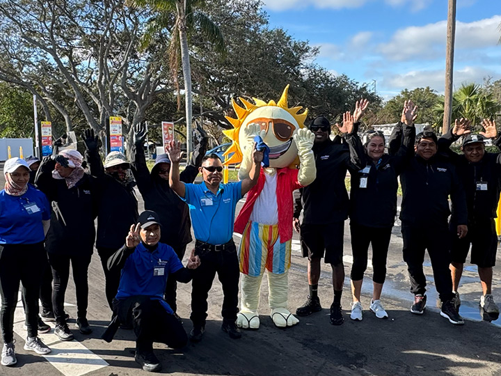 The Sunshine crew waving alongside Sunny the mascot in the parking lot