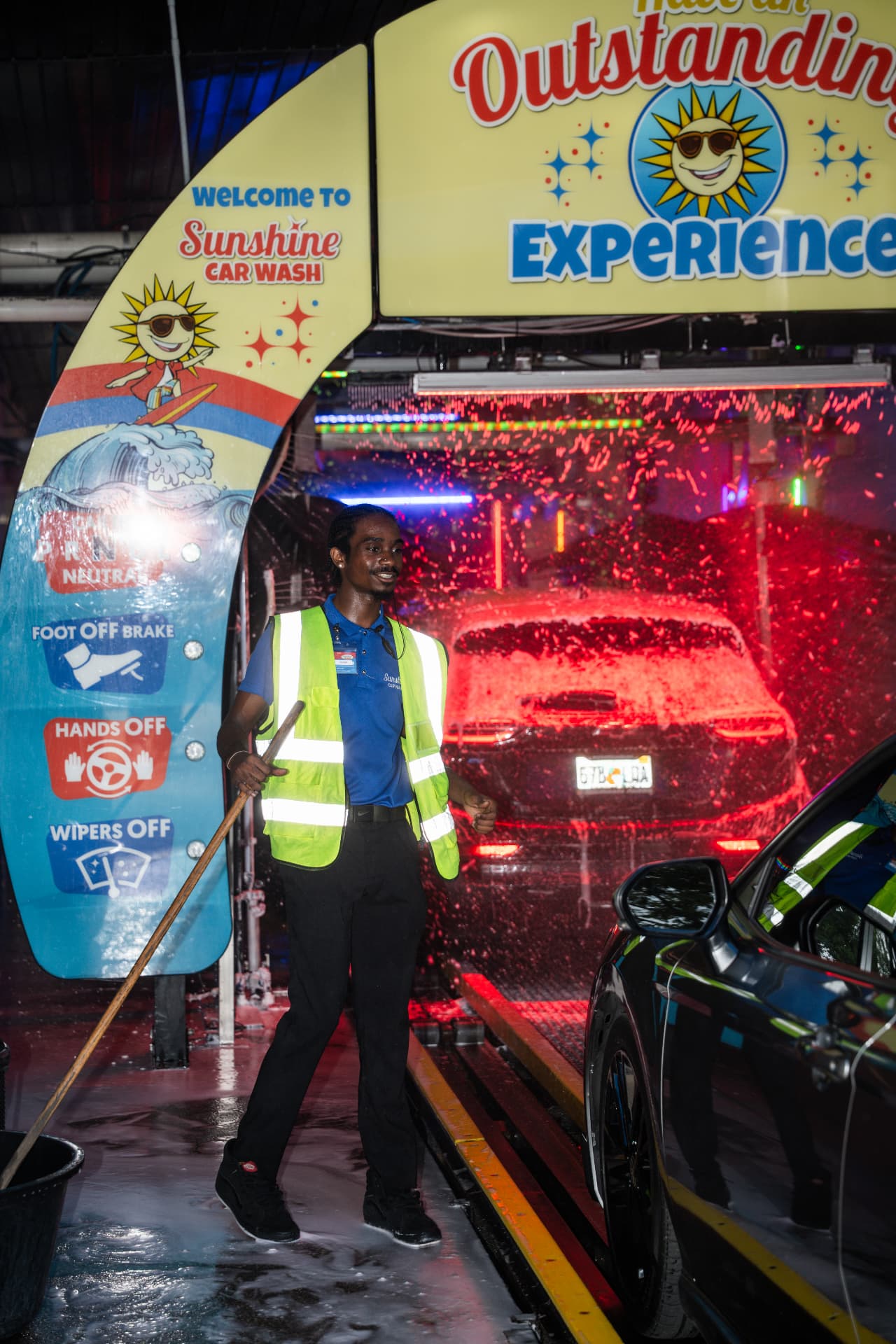 A Sunshine team member welcoming a driver into the colorful wash tunnel