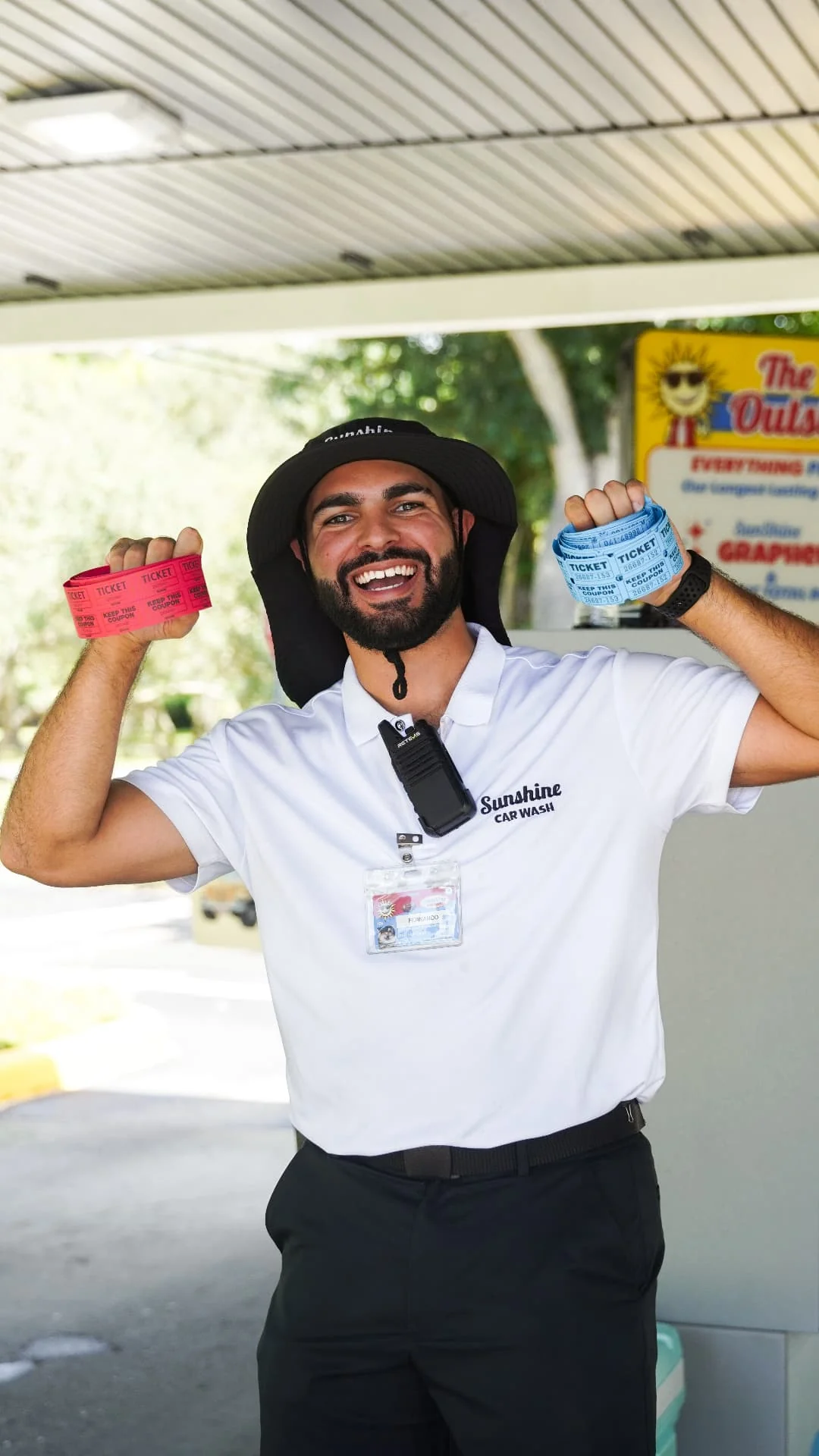 A smiling Sunshine greeter showing off colorful wash ticket wristbands