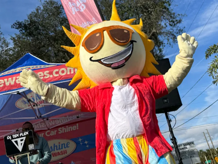 Sunny the mascot cheering with arms raised at a community event