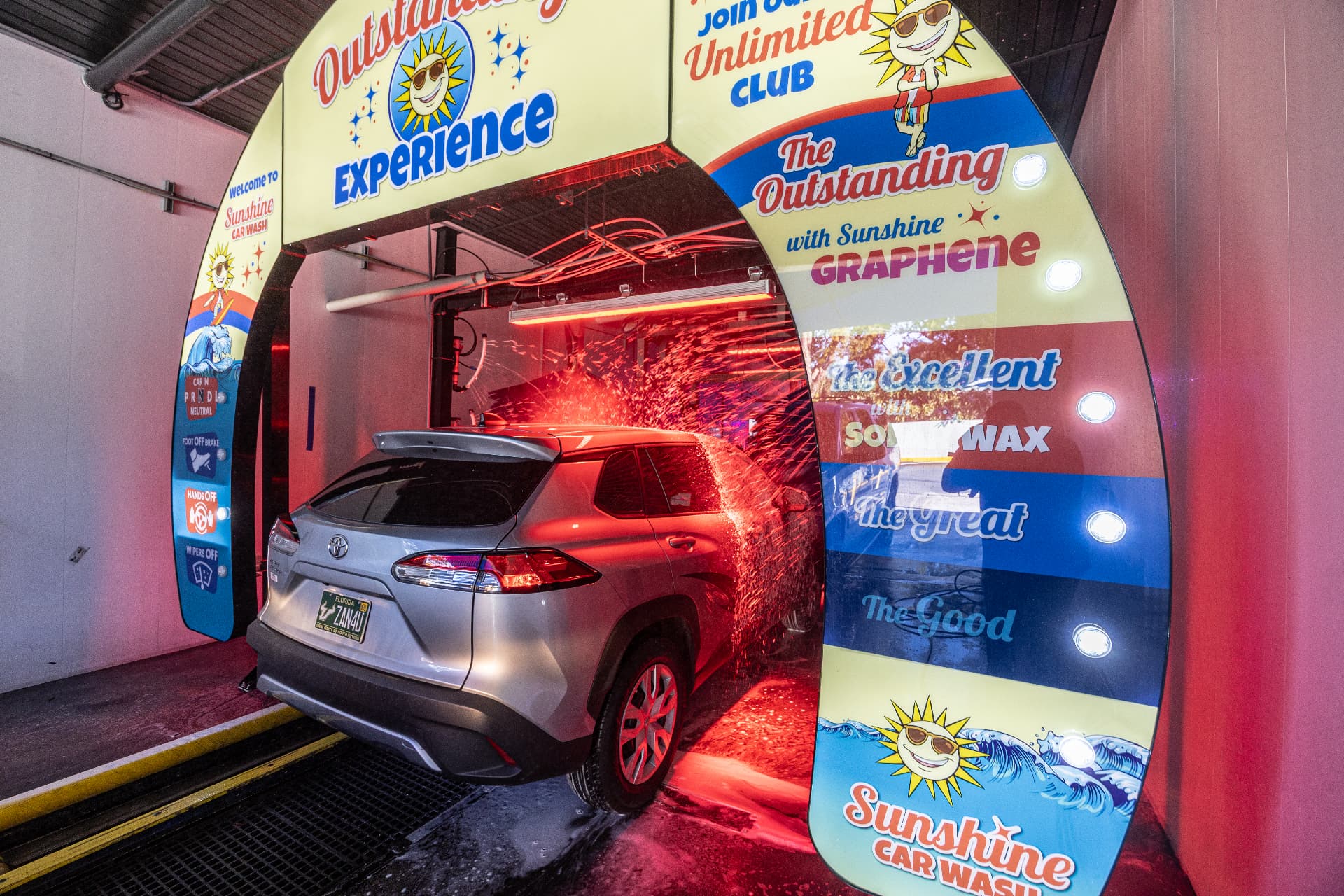 A car passing beneath the glowing Outstanding Experience arch inside the Fowler Avenue tunnel