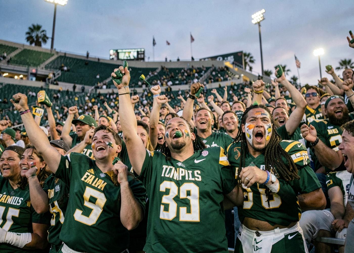 College football fans in green and gold cheering from the stands